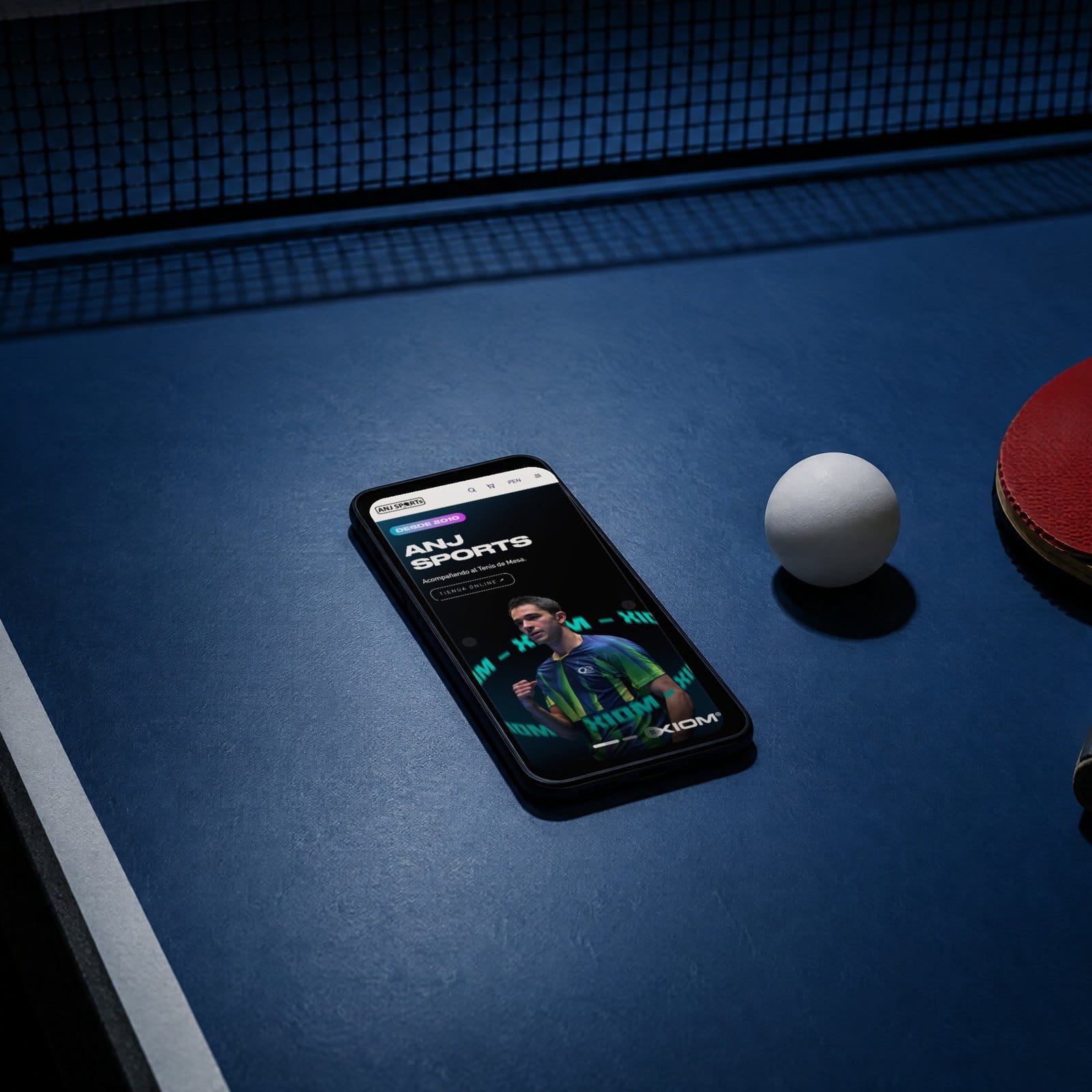Un celular sobre una mesa de tenis de mesa, junto a la pelota y la paleta, con la portada de anjsports.com