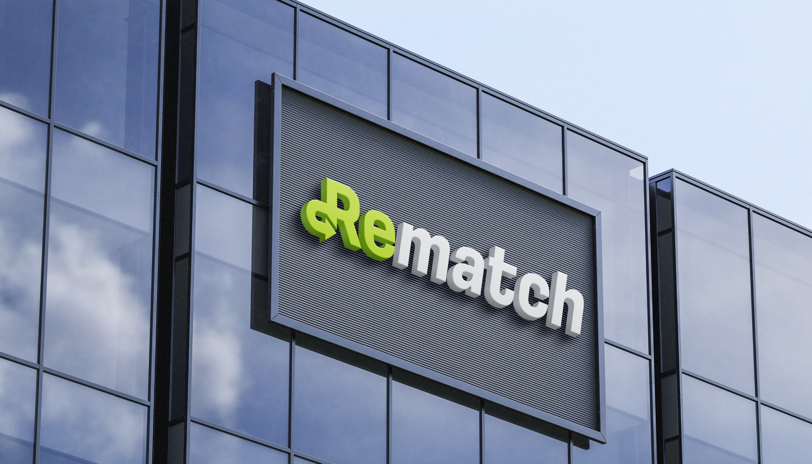 Maqueta del logotipo de Rematch en relieve sobre la fachada de vidrio de un edificio